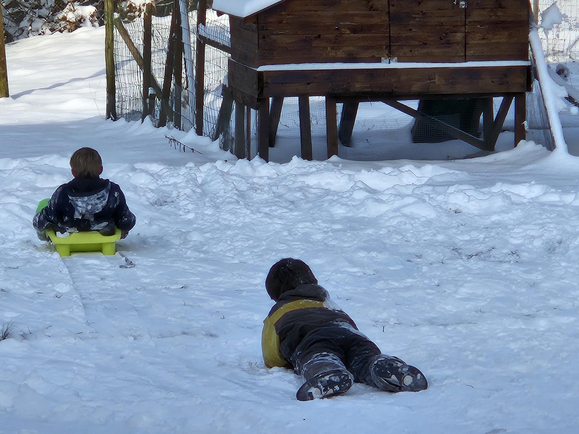 Deux enfants qui font de la luge en hiver au vieux moulin